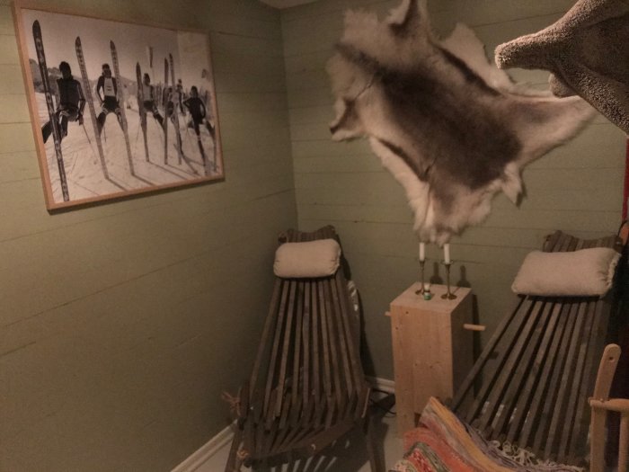 Interiör av en basturelax med trästolar, fårskinn, tavla med skidmotiv och en handdukshängare.