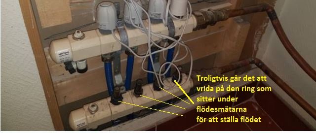 Golvvärmefördelare med flödesmätare och termostater, anvisning markerar inställningsring.