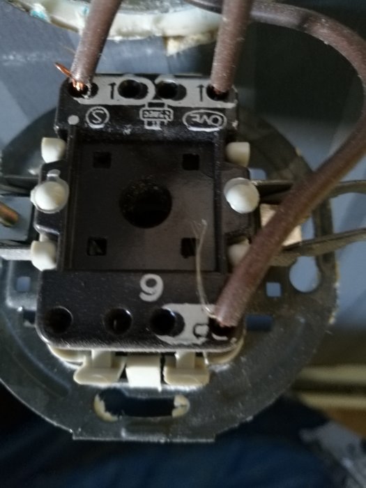 Bild på en strömbrytare med svart fas in-kabel och två bruna kablar ut.