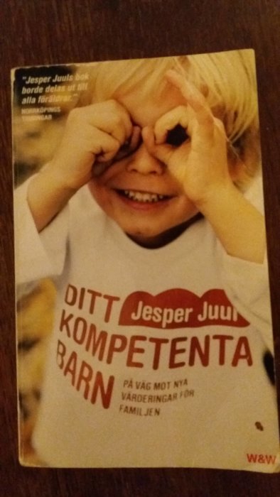 Bokomslag till "Ditt kompetenta barn" av Jesper Juul, barn ser genom handkikare.