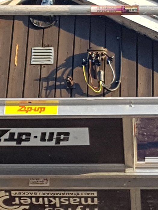 Inkommande elkabel på fasad med gammal kopplingsdosa och synliga kablar, oestetisk installation.