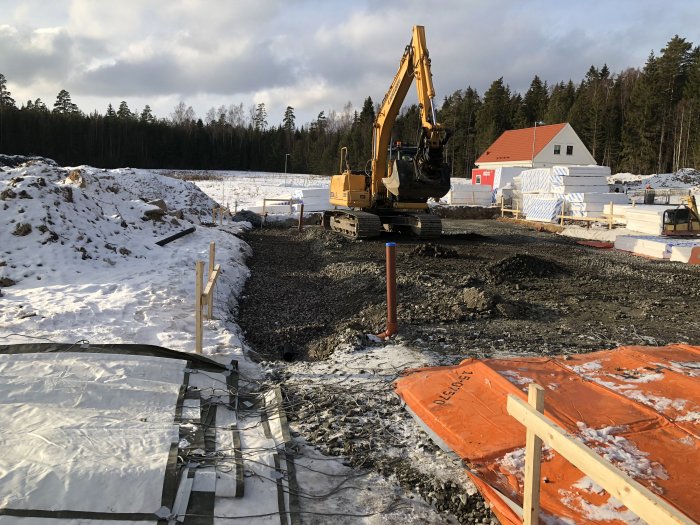 Byggarbetsplats med fyllnadsmassor, grävmaskin och förberedelser för gjutning av betongplatta.