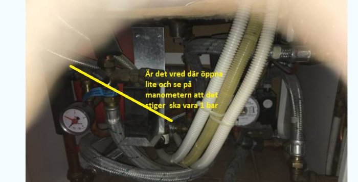 Röranslutningar under diskbänk med manometer som visar 1 bar, och en pil pekar mot ett vred.