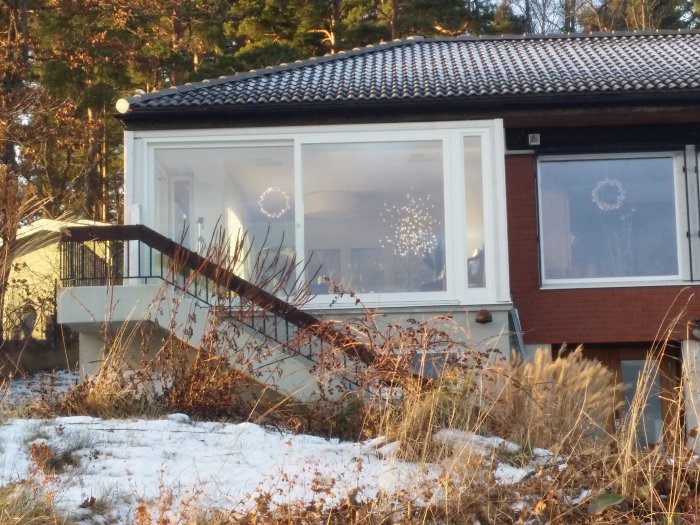 Ett enfamiljshus med tegelfasad och snöfläckad trädgård i förgrunden.