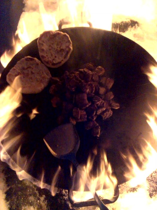 Naanbröd och skuret kött som tillagas över öppen eld på en 58 cm Muurikka stekhäll i ett odlingsområde.