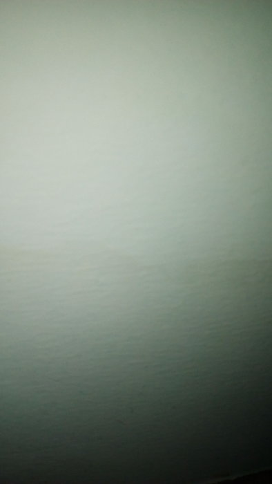 Missfärgning på en ljus, strukturerad väggyta med en mörkare fläck i hörnet.