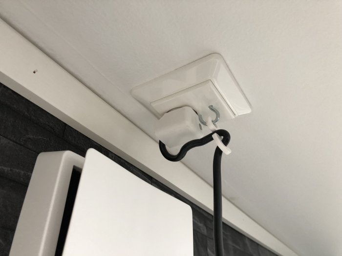 Moddat eluttag med skruvkrok och smältlim för att hålla fönsterlampans kabel på plats.