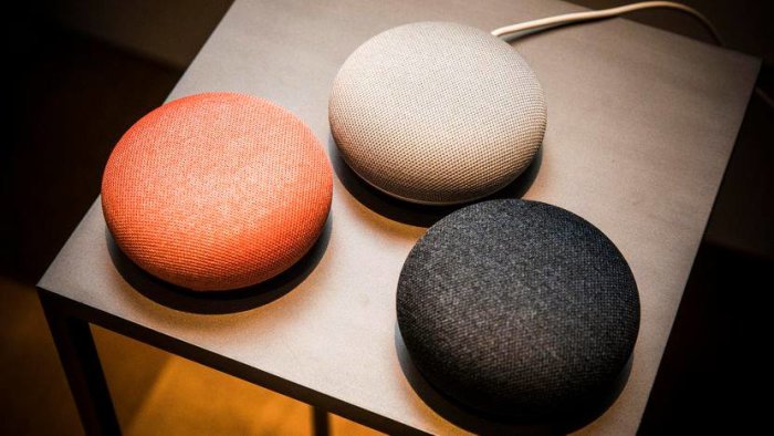 Tre Google Home enheter i olika färger på ett bord.