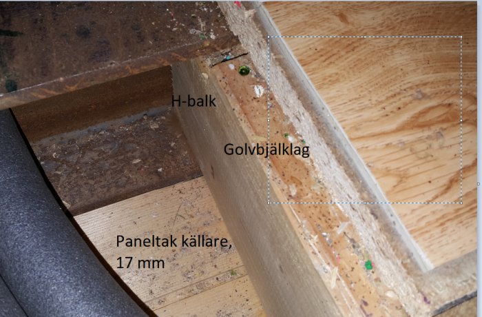 Delvis synligt golvbjälklag bredvid en H-balk, anteckningar om paneltak och tjocklek på en byggplats.