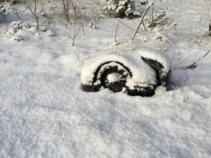 Däck halvt dolt i snö under vinterdag.