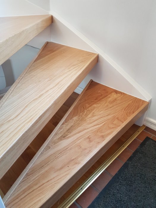 Renoverad trappa med nya trästeg monterade på befintliga trappsteg.