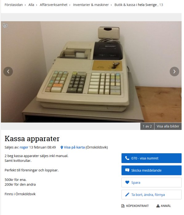 Äldre beige kassapparat med knappsats och skärm på ett bord, inkluderar kvittorulle och manual.