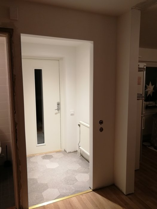 Nymålad dörrkarm och vägg i en hall med synligt slip- och målningsarbete runt dörröppningen.