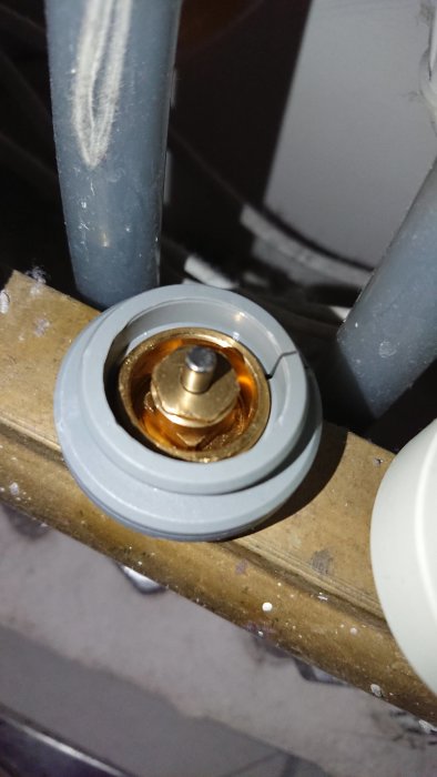 Närbild av en ventilspindel för golvvärme med synliga rör, troligtvis för justering av värmen.