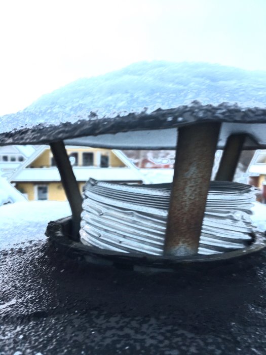 Utsnitt av takhuven med flexrör och synligt tätningsskikt, omgivet av snö och bakgrund av hus.