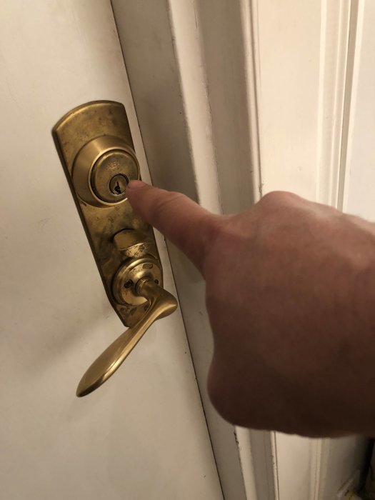 Hand pekar på en gammal dörrhandtag för att illustrera en köldbrygga där frost kan bildas.