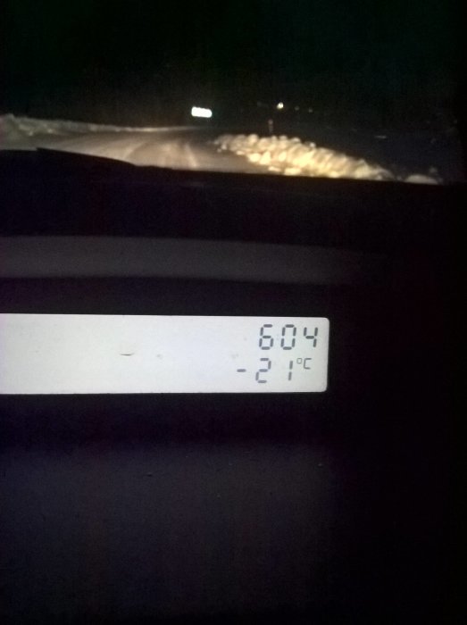 Bilens termometer visar -21 grader Celsius, nattlig väg i bakgrunden.