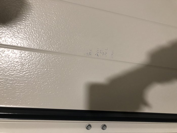 Nyinstallerad vit garageport med estetiska skador i form av blå märken på den släta ytan.
