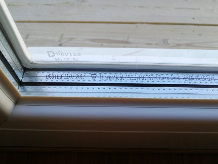 Fönsterkasett med text och logotyp för tillverkaren Drutex samt datumstämpel och standardnummer.