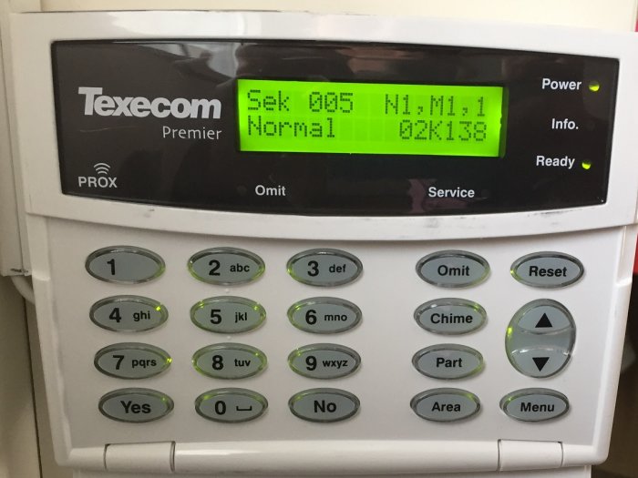 Larmsystemets kontrollpanel som visar 'Normal' status på displayen, indikatorer för ström och beredskap är tända.