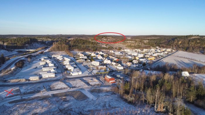 Flygbild över bostadsområde med markerad tomt och omgivande berg som skuggar tomten på kvällen.