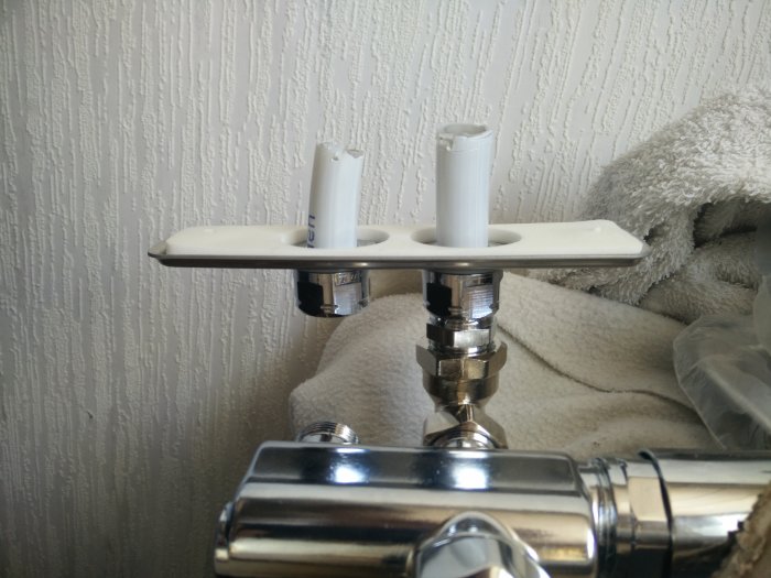 Väggmonterad Vatette väggbricka kopplad till rör som leder till handdukstork.