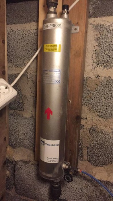 Luftkatalysator för vattenbehandling monterad på vägg i krypgrund med dräneringsventil.