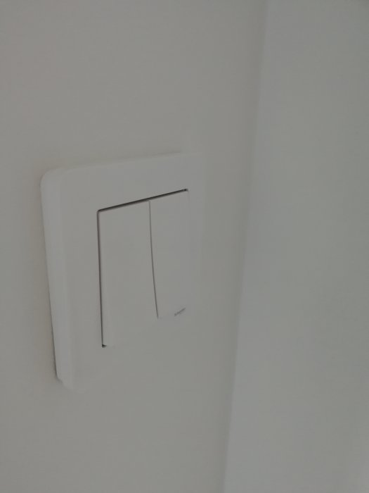 Nyinstallerad vit strömbrytare på en nymålad vit vägg
