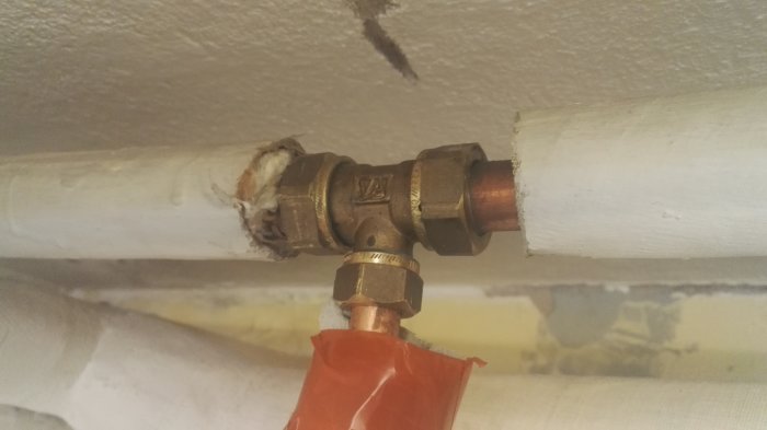 VVS-installation med kopplingar för varm- och kallvattenrör i en konstruktion under tak.