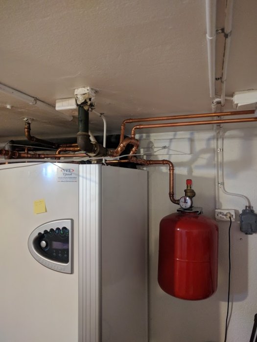 VVS-installation i taket med rör och ett rött expansionskärl bredvid en panna.