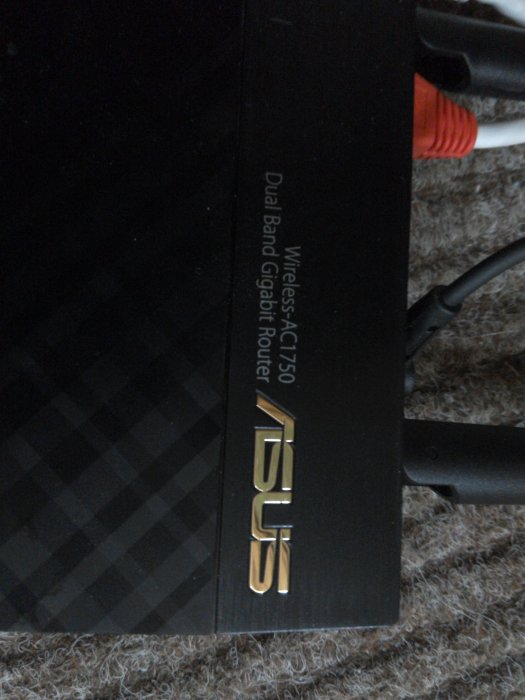 Närbild på en ASUS dual-band gigabit router med anslutna kablar.