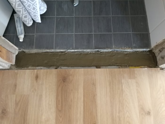 Nybetongad tröskel mellan kakel och trägolv i renoveringsprojekt.