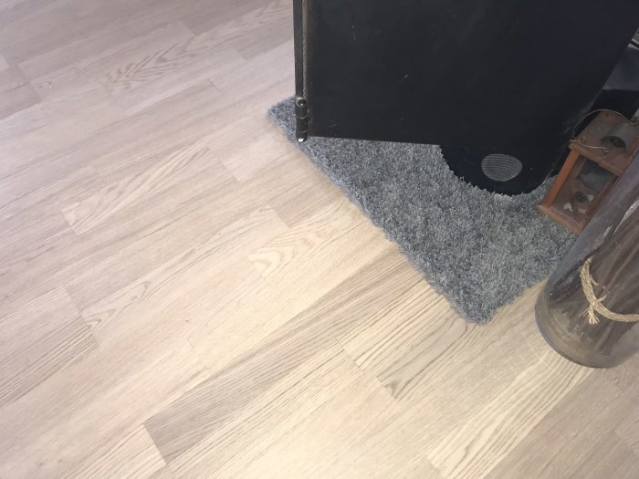 Ett trägolv med en skräddarsydd utbytbar matta runt en spisens kant.