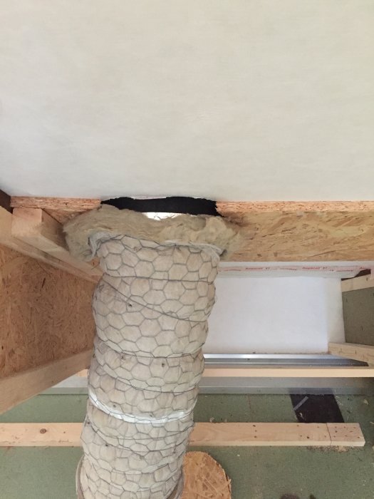 Avluftningsrör omslutet av stenullsisolering på en övervåning under renovering.