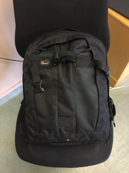 Svart Lowepro kameraväska på en svart stol, knappt använd.