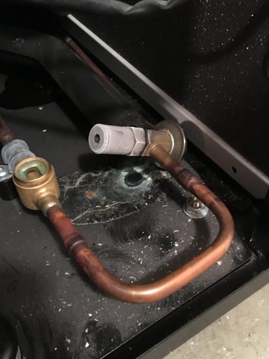 Kopparledningar och anslutningar med möjliga läckagetillstånd och smuts på svart yta.