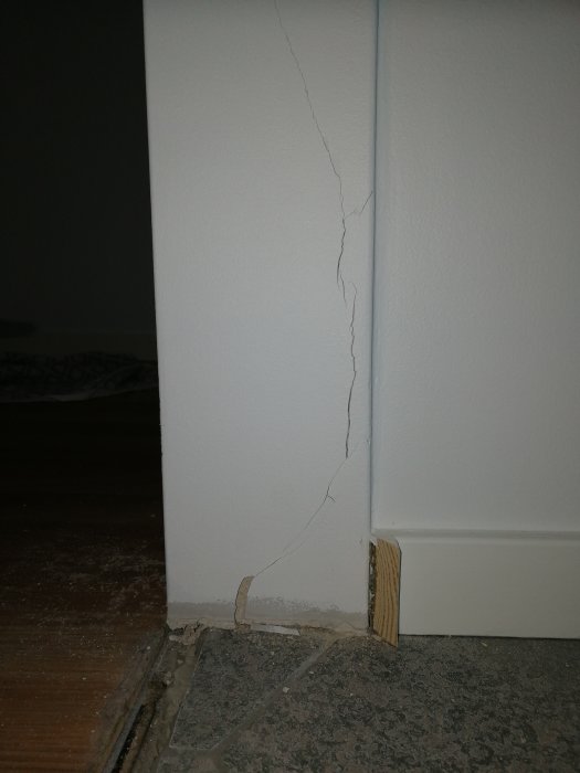 Sprucken vägg intill nyinstallerad dörrkarm och tröskel.