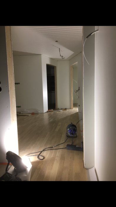 Renoverat rum utan trösklar med synliga golvinstallationer och byggverktyg.