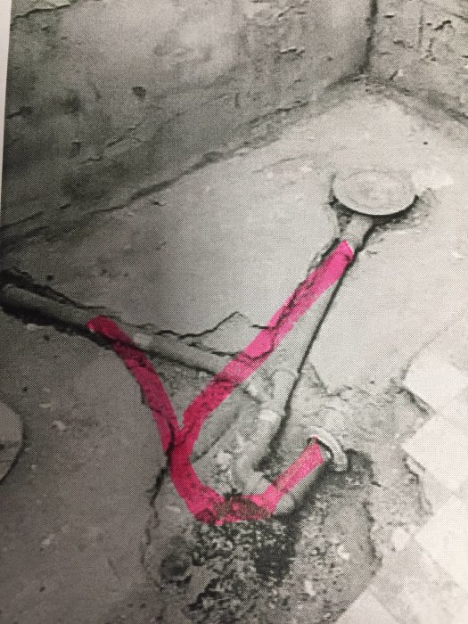 Betonggolv med uppritade rosa linjer som markerar den föreslagna dragningen av rör till badrumsinstallationer.