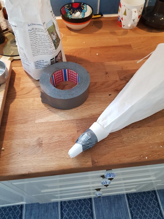 En spritspåse lagad med silvertejp på ett köksbord bredvid en rulle tejp.