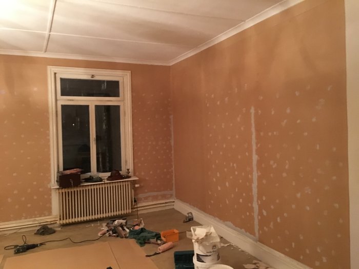 Renoveringsprojekt med vägg förberedd för spackling och målning i ett tomt rum.