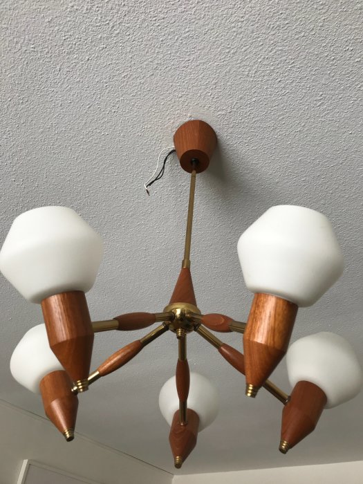 Brun och guldig retrolampa med fem armar och vita skärmar, monterad på vägg utan synlig kabel.
