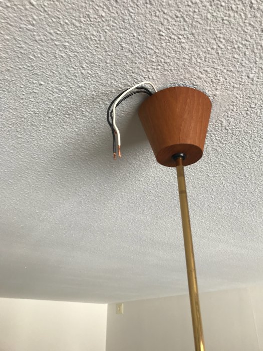Retrolampa monterad på tak med oanslutna svarta och vita elsladdar som sticker ut ur brun träkåpa.