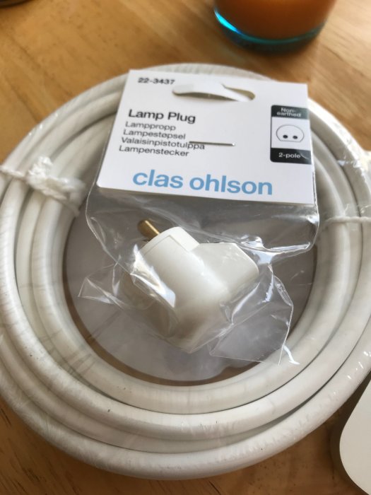 Lampplug och vit elkabel rullad på bord, för användning med retrolampa.