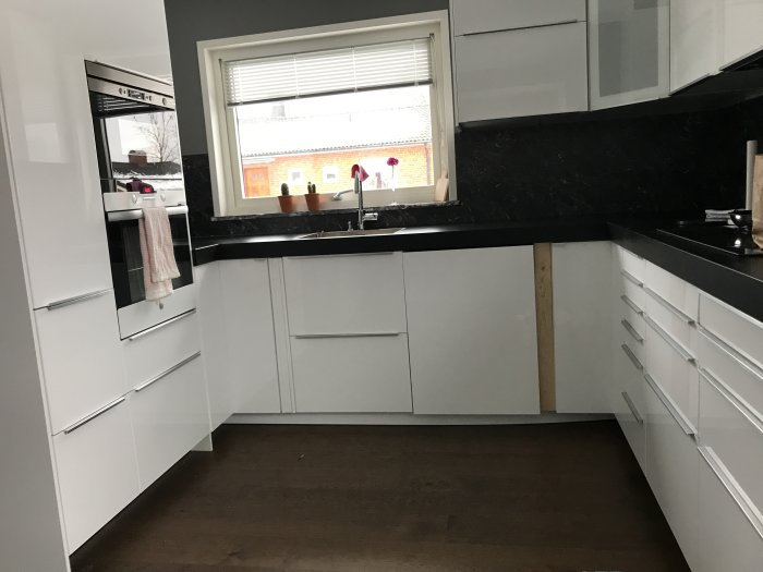 Kök under renovering med öppen diskmaskinslucka och en omonterad stänkpanel.