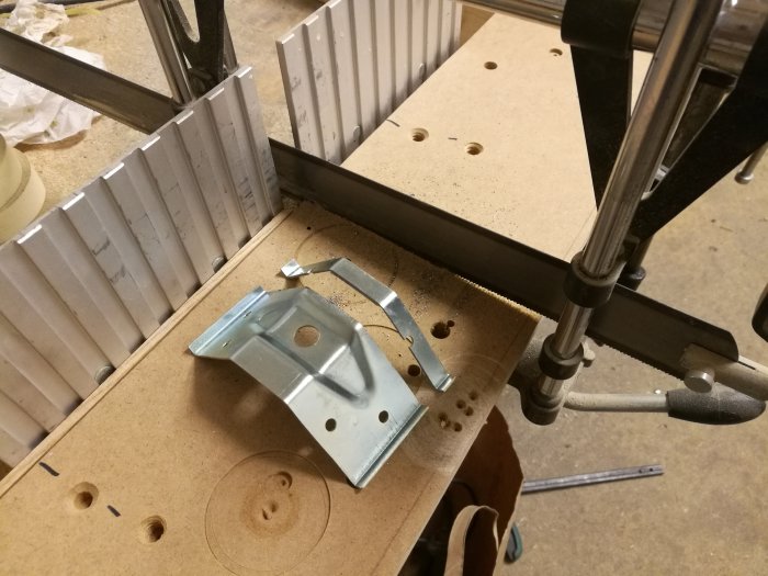 Arbetsbänk med en klämskruv som håller fast en metallprofil vid kapning, och verktyg på en träyta.