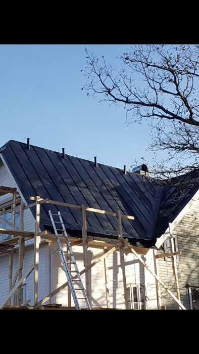 Renoveringsarbete på putsvilla med nytt plåttak och takstosar för ventilation på taknocken.