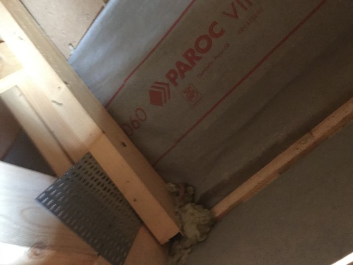 Vy under ett altantak med exponerad isolering och träreglar, Paroc vindskydd synligt.
