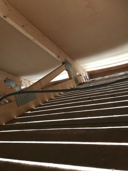 Altanens undertak med vindskydd i form av träribbor, fästdetaljer synliga, isolering ej installerad.