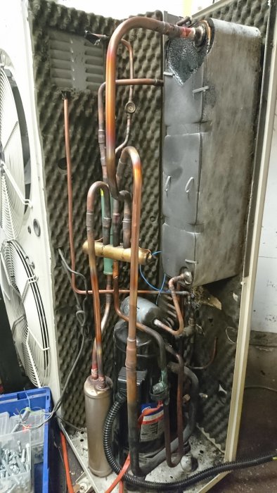 Internt av en luftvattenvärmepump under konstruktion, med kopparledningar och komponenter.